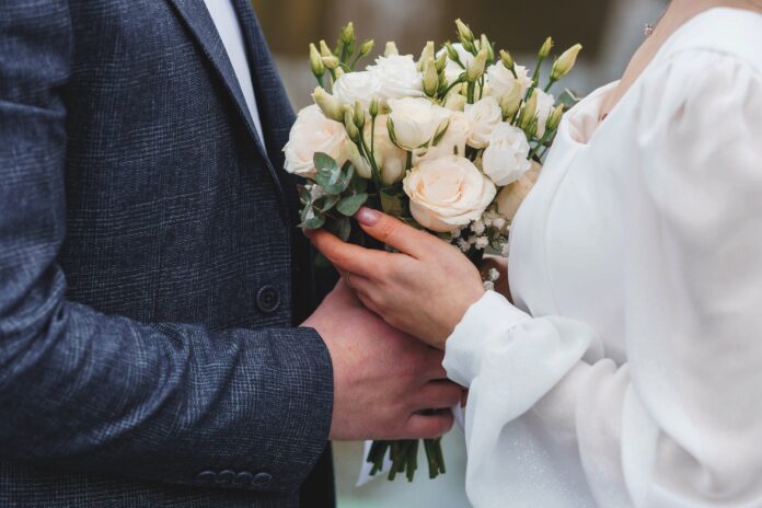 Elegant Wedding Couple Holding a Beautiful Bouquet of White and Green Flowers.